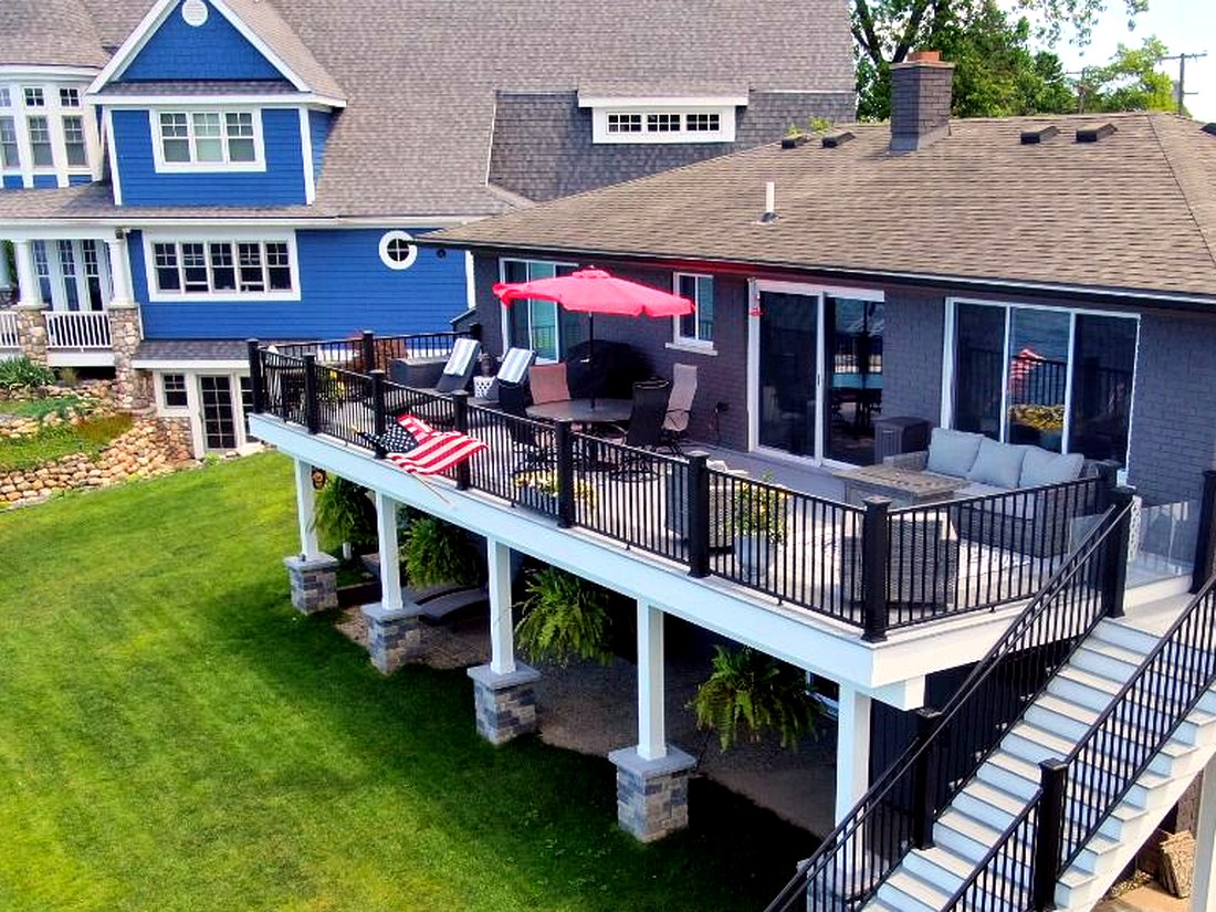 Drone aerial of a large elevated Trex composite deck with black aluminum railing and stone-clad support columns
