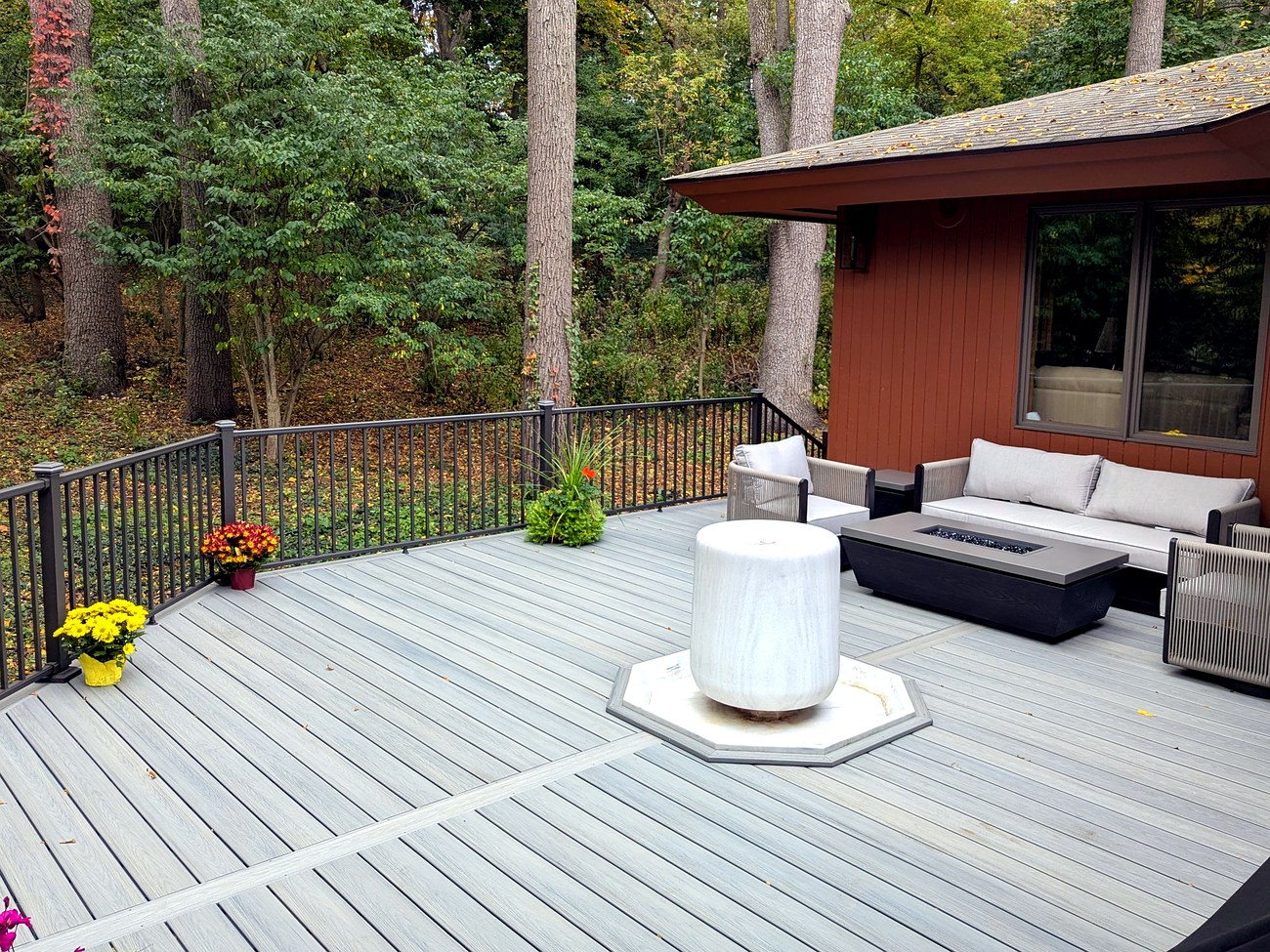 Octagon Trex composite deck with built-in fire pit lounge seating, surrounded by mature trees