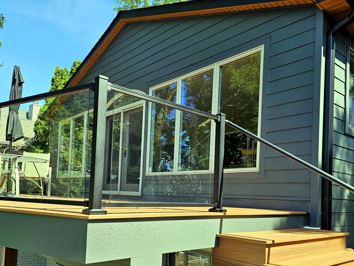 Elevated Trex composite deck with sleek frameless glass railing built by Supreme Deck Builders